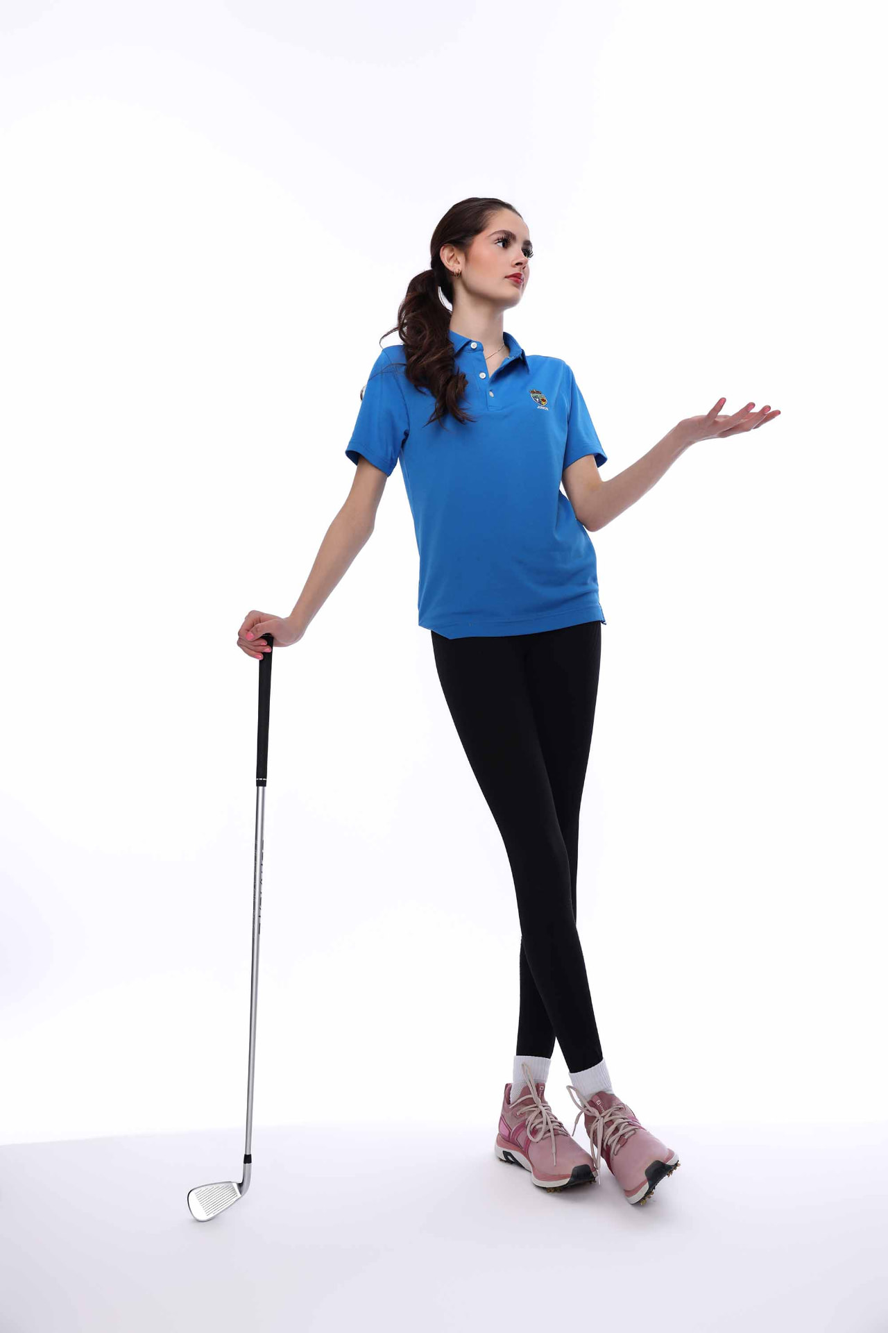 Ellie Gray in golf apparel holding a club against a white backdrop