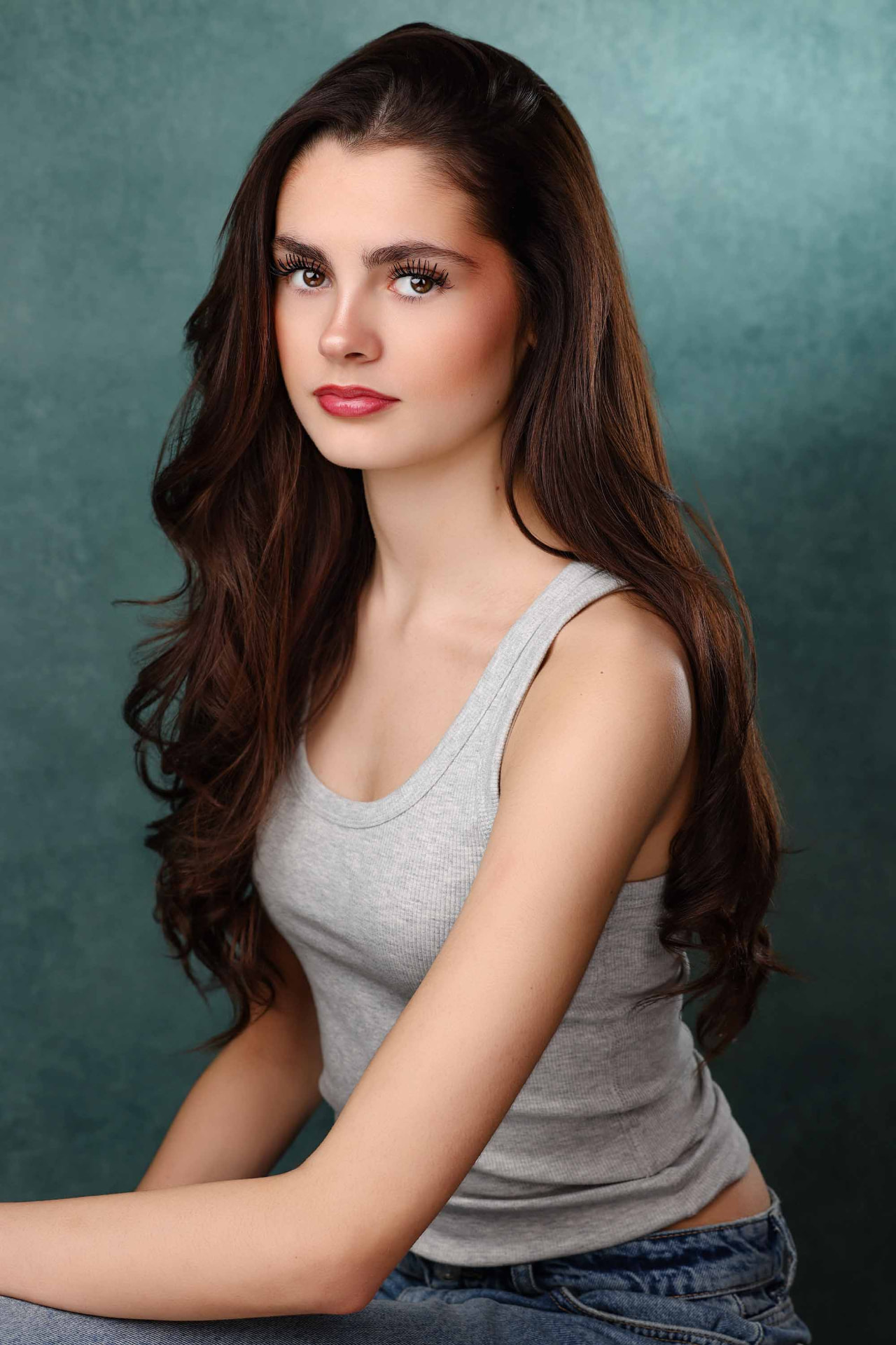 Ellie Gray portrait in a grey vest against a teal backdrop