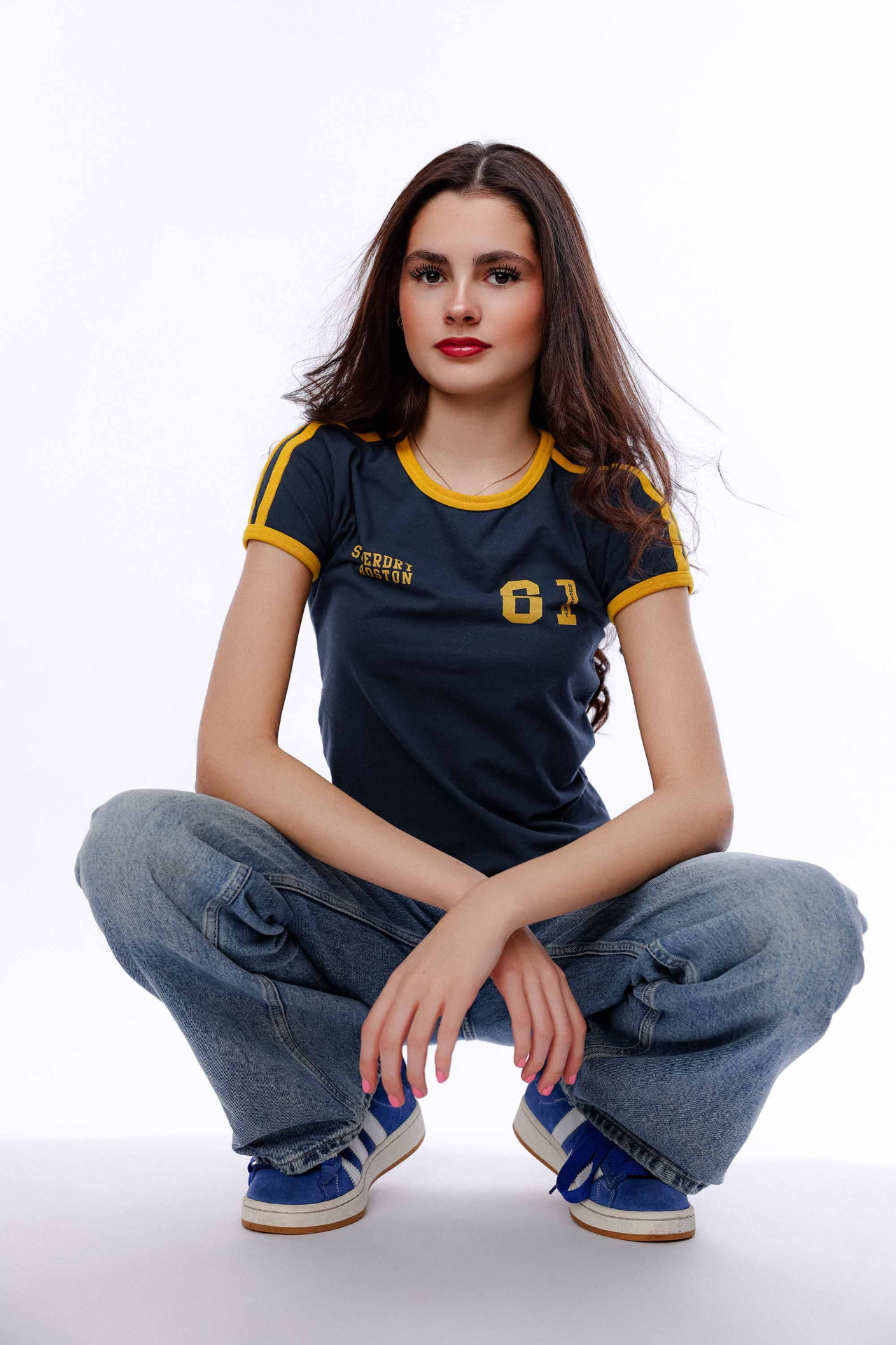Ellie Gray crouching in a navy ringer tee against a white backdrop