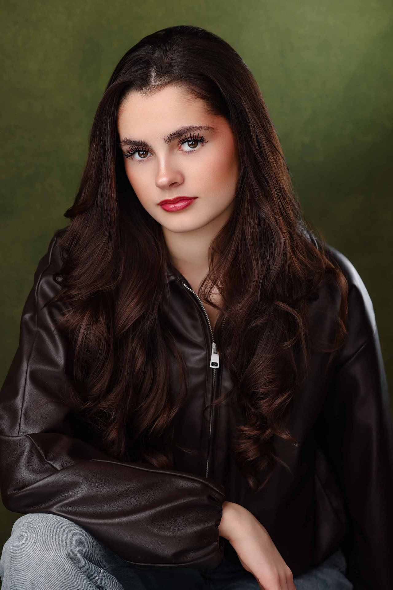Ellie Gray in a black leather jacket against an olive backdrop